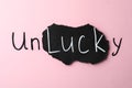 Word UNLUCKY on pink background