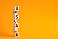 The word upscale on wooden cubes against yellow background. Upscale business, high-end expensive goods or high resolution format