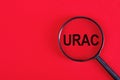 The word URAC on magnifying glass, redbackground, business concept