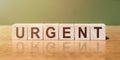 The word URGENT on wooden cubes on a table, on a beautiful background