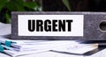 The word URGENT is written on a gray file folder next to documents. Business concept