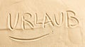 The word Urlaub written in golden beach sand