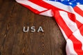 the word USA laid with silver metal letters on wooden board surface with crumpled flag of United States of America upper