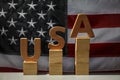 Word USA made with wooden letters and cubes on table against national flag Royalty Free Stock Photo