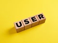 The word User on wooden cubes on yellow background. Technology concept