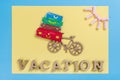 Word vacation abstract wooden letters. Background blue yellow, image of heap of suitcases on bicycle