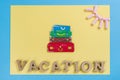 Word vacation abstract wooden letters. Background blue yellow, image of heap of suitcases
