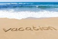 Word vacation written on sandy beach near sea
