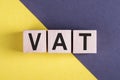 Word VAT on wooden cubes on yellow - gray background