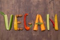 Word Vegan written with letters from different vegetables, fruits, nuts on rustic wooden background. Organic vegan food Royalty Free Stock Photo