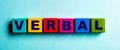 The word VERBAL is written on multicolored bright wooden cubes on a light blue background Royalty Free Stock Photo