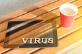 Word VIRUS with wooden vintage letters, background tablet on wooden bench, cup of coffee Royalty Free Stock Photo