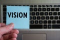 Word VISION on sticky note hold in hand on keyboard background