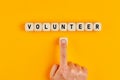 The word volunteer written on wood blocks with a male hand pushing the button. Concept of volunteering Royalty Free Stock Photo