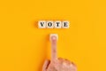 The word vote written on wooden cubes with a male hand pushing the voting button. Online voting concept in politics or business Royalty Free Stock Photo