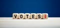 The word votes with downward arrow on wooden cubes. Elections and declining votes concept Royalty Free Stock Photo