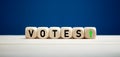 The word votes with upward arrow on wooden cubes. Elections and votes concept Royalty Free Stock Photo