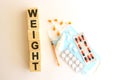 The word WEIGHT is made of wooden cubes on a white background. Medical concept