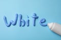 Word White written with toothpaste and tube on light blue background, flat lay Royalty Free Stock Photo