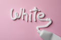 Word White written with toothpaste and tube on pink background, top view Royalty Free Stock Photo