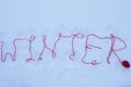 The word WINTER is written on the snow with a woolly red thread. Winter concept. Outdoors