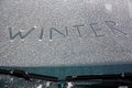 Word winter written on snowy windshield