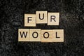 The word from wooden letters lies on a black gray fur