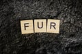 The word from wooden letters lies on a black gray fur