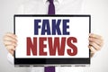 Word, writing Fake News. Business concept for Hoax Journalism Written on tablet laptop holding by the man blurred background. Busi Royalty Free Stock Photo