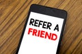 Word, writing handwriting Refer A Friend. Business concept for Referral Marketing Written on mobile phone cellphone, wooden backgr