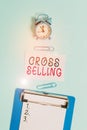 Word writing text Cross Selling. Business concept for to sell complementary products to an existing customer Alarm clock clipboard