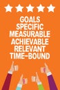 Word writing text Goals Specific Measurable Achievable Relevant Time Bound. Business concept for Strategy Mission Men women hands