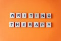 Word writing therapy. The phrase is laid out in wooden letters top view. Motivation. Orange flat lay background Royalty Free Stock Photo