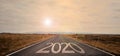 The word 2020 written on highway road in the middle of empty asphalt road at golden sunset and beautiful blue sky. Royalty Free Stock Photo