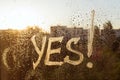 The word yes on the window with water drops on sunny background, yes written with white toothpaste Royalty Free Stock Photo