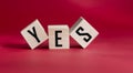 The word YES is written in black letters on wooden blocks. Spell message yes on a red background. Royalty Free Stock Photo