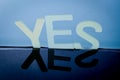 The word Yes written in plastic letters on a black mirroring surface.