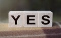 The word YES is written on wooden cubes. Wooden cubes in the open air, overlooking the countryside. For business related design.