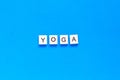 The word YOGA written in wooden letterpress type on a blue background. flat layout. top view Royalty Free Stock Photo