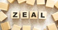 The word ZEAL consists of wooden cubes with letters, top view on a light background.