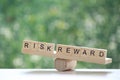 Wording risk and Reward on wood block on natural green background, Business investment and Risk management concept.Financial risk