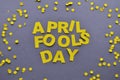 The words April Fools' Day of yellow paper are laid out inside a circle of confetti on a gray background close-up