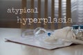 Words ATYPICAL HYPERPLASIA. Plastic vaginal speculum, pills and other tools in the background