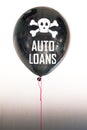 The words auto loans in white and a skull and cross bones on a balloon illustrating the concept of a debt bubble