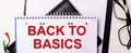The words BACK TO BASICS is written in red in a white notebook next to black-framed glasses Royalty Free Stock Photo