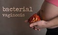 Words BACTERIAL VAGINOSIS. Young pregnant between 30 and 35 years old woman keeps rose blossom close to  her belly in the Royalty Free Stock Photo