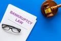 Words bankruptcy law written on the documents near judge gavel on blue background top view copy space