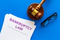 Words bankruptcy law written on the documents near judge gavel on blue background top view copy space