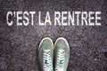Words C`est la rentree meaning back to school written on asphalt road with sneakers shoes, high school and college con