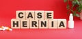 The words CASE HERNIA is made of wooden cubes on a red background. Medical concept.